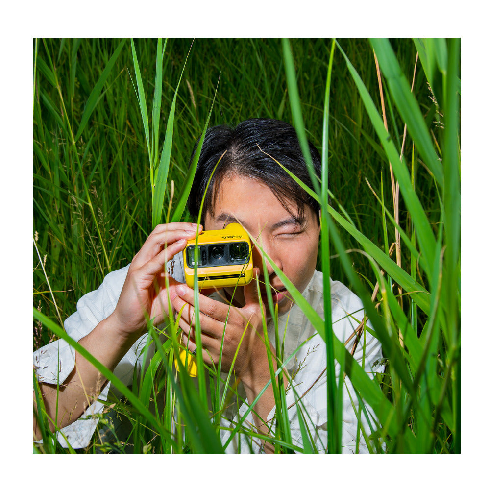 Person taking a photo with the yellow Polaroid Go Gen 3 Pikachu Edition in tall grass