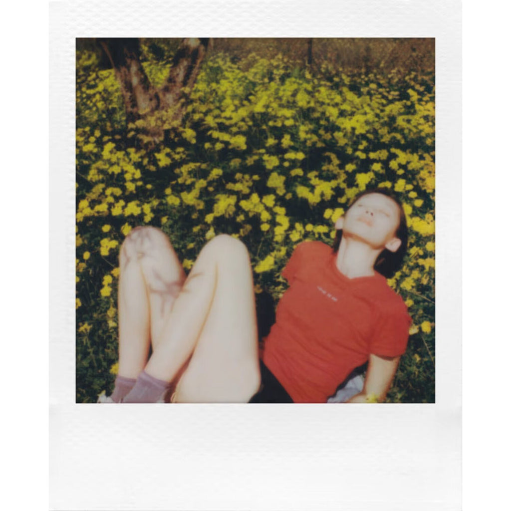 Instant photo of two people lying in a field of yellow flowers, taken on Polaroid Go film