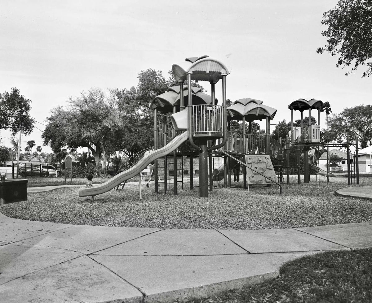 Black-and-white playground structure with slides, climbing walls, and canopy roofs