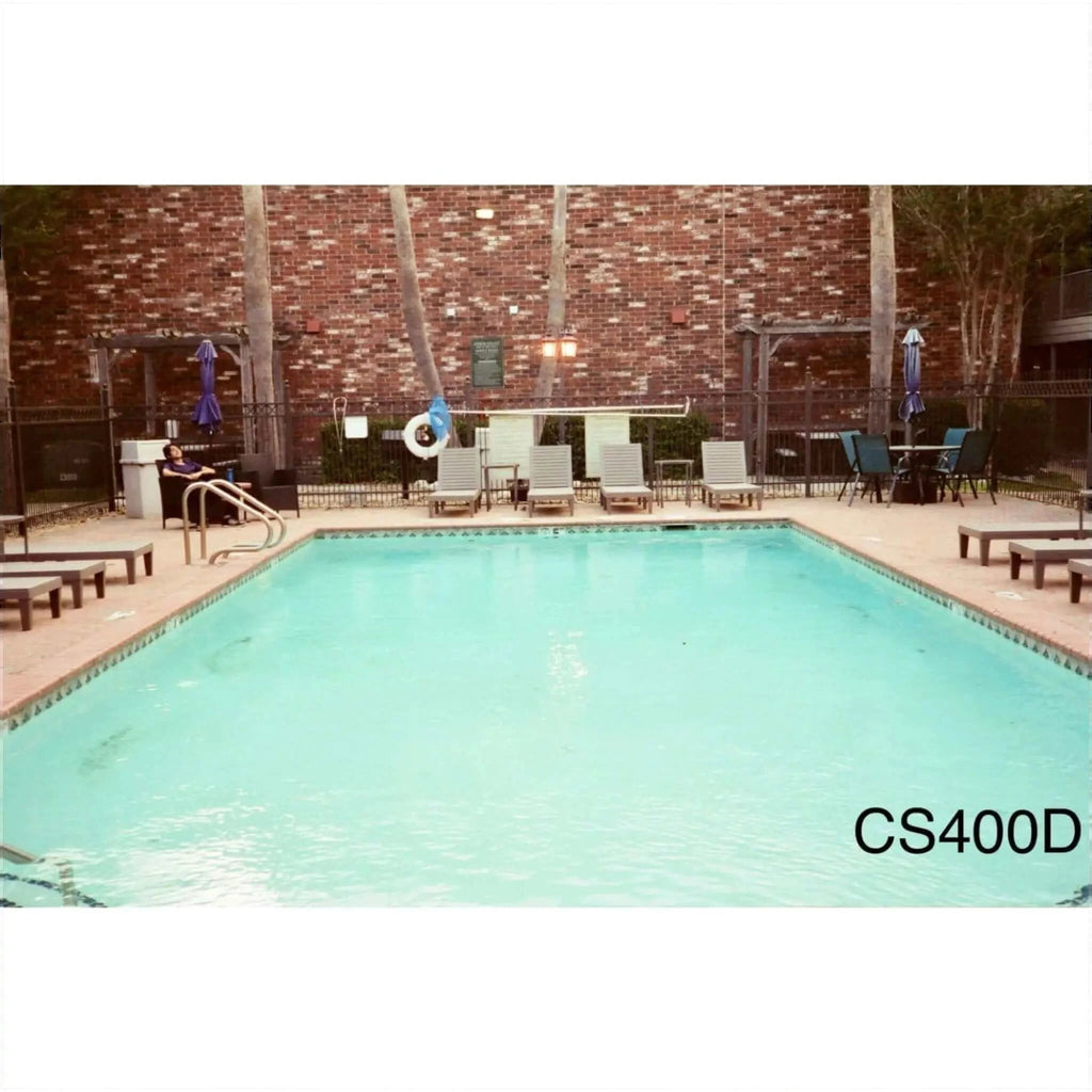 Rectangular in shape with clear turquoise water and tiled edges, surrounded by lounge chairs and a brick wall
