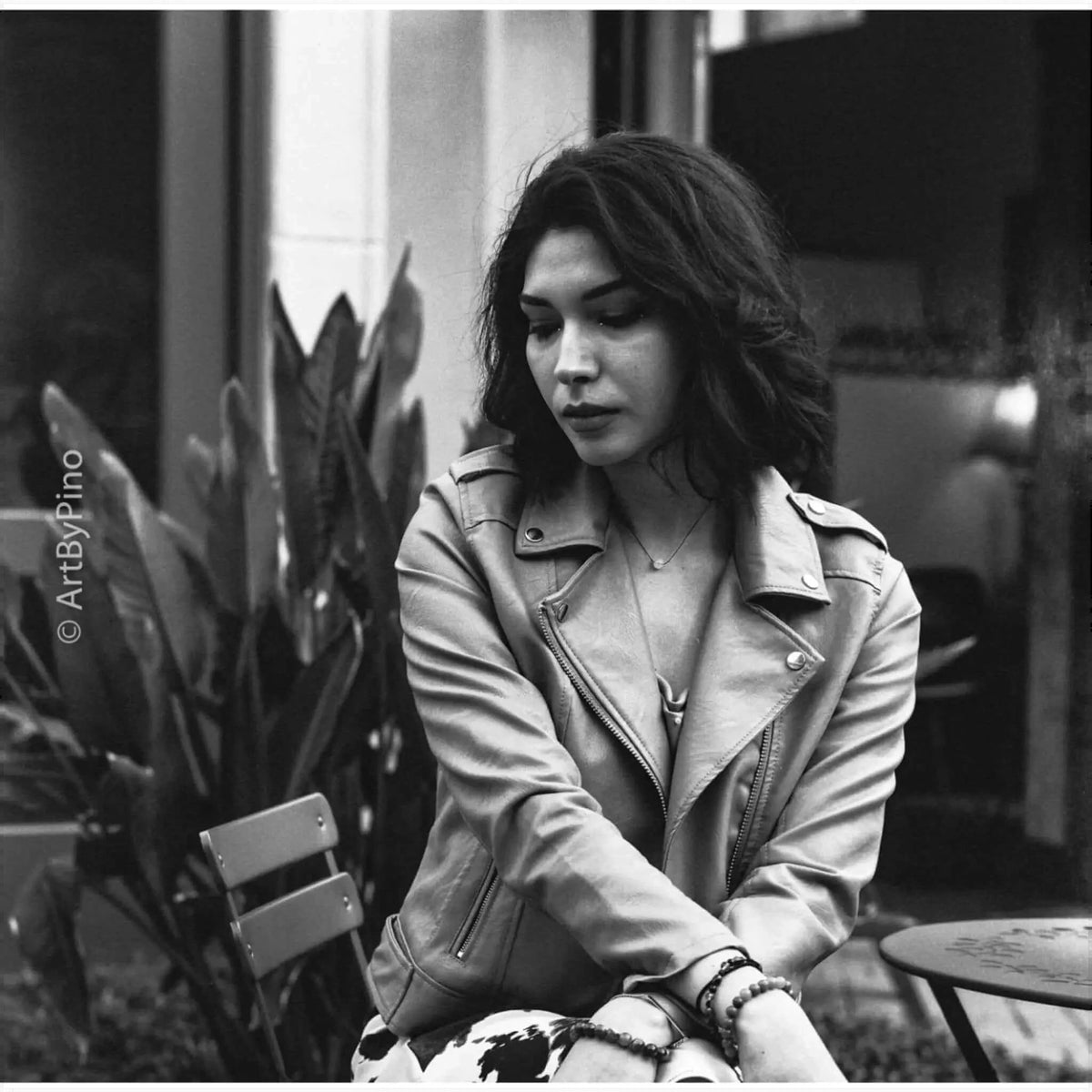 A woman wearing a classic leather biker jacket with silver zippers and button details.