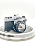 Silver and black asahi pentax k1000 film camera with a textured leather grip.
