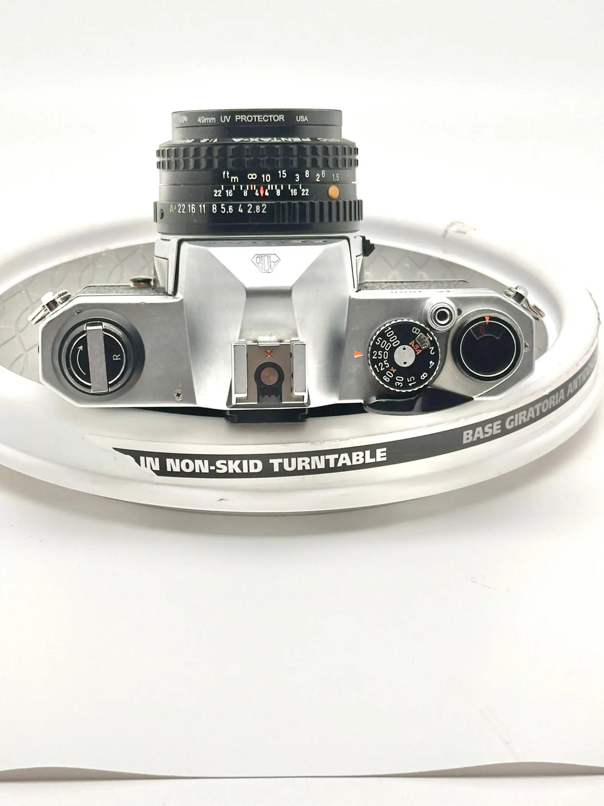 Silver-bodied canon ae-1 film camera with a black 40mm uv protector lens mounted on top.