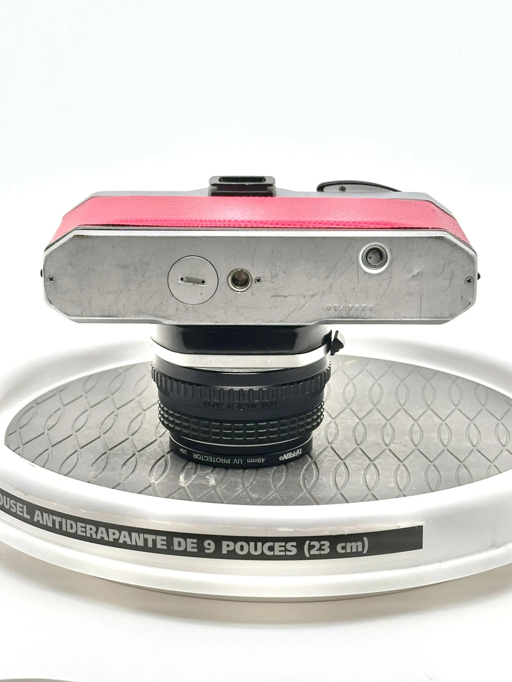 A vintage silver-bodied camera with a vibrant pink textured top panel and a black lens mounted on it.