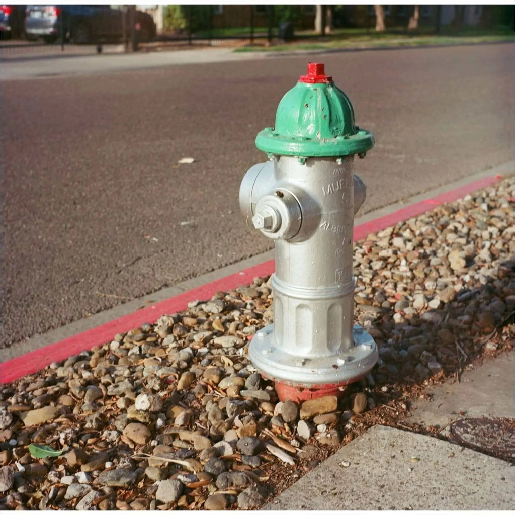 A green and silver fire hydrant with a red cap, featuring embossed markings on its body.