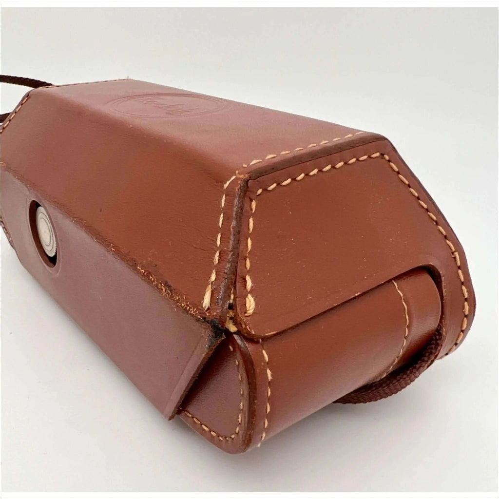 Brown leather camera case with tan stitching and a circular metal clasp.