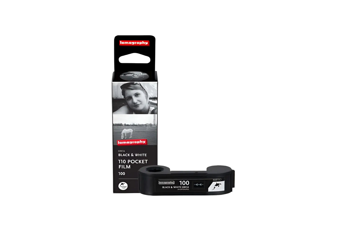 Black and white 100 iso film roll in a sleek black packaging, branded as ’lomography’ with vintage photographic imagery on the box.