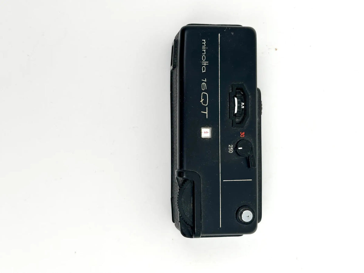 Black minolta 7eqt film camera with a compact, rectangular body and visible dials for shutter speed settings.