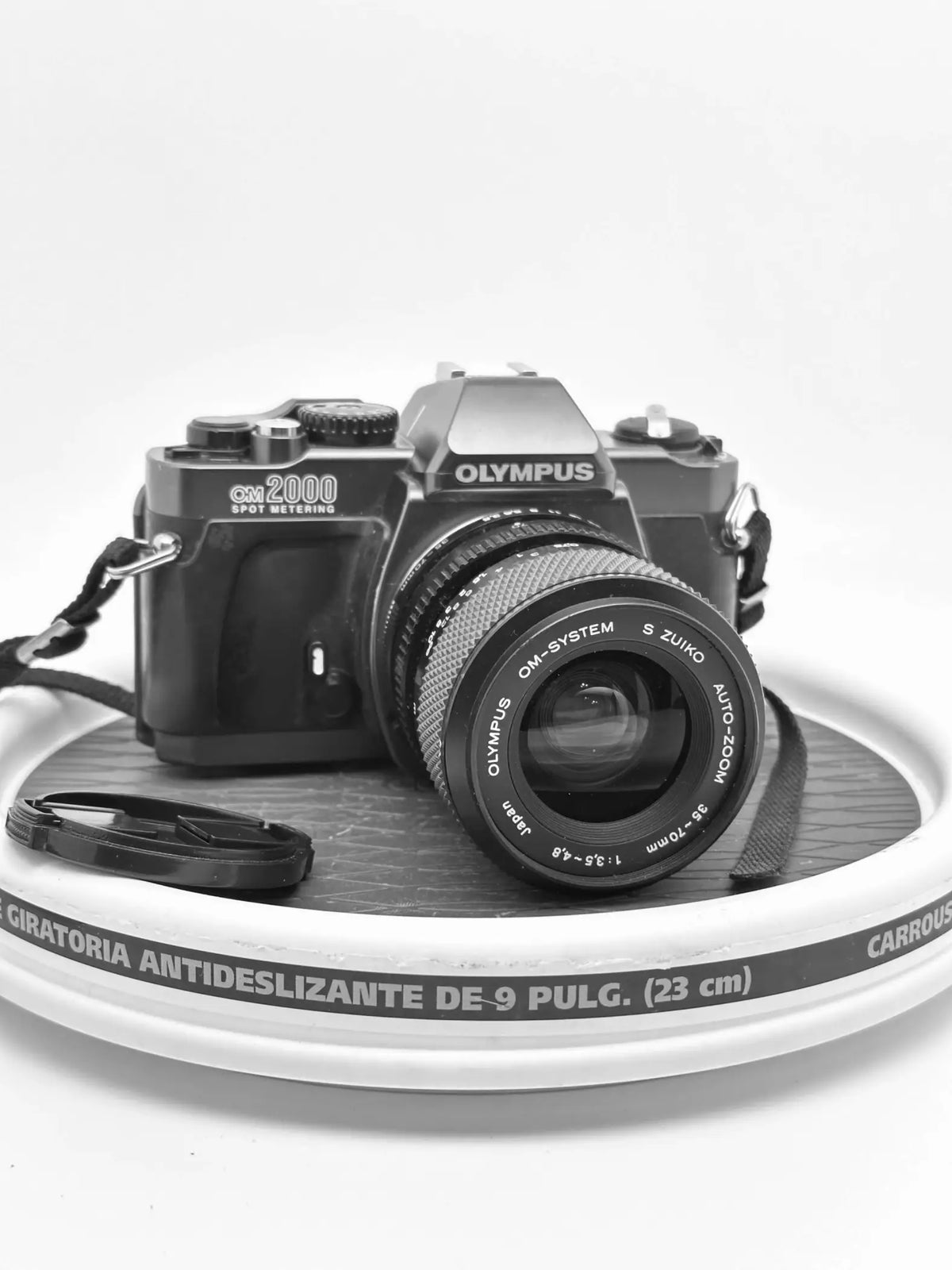 Black olympus om-2000 film camera with a zoom lens, featuring textured grip and classic dials.