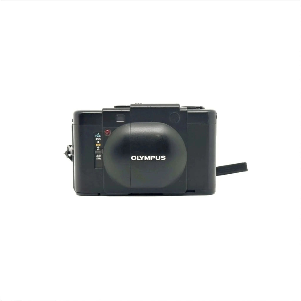 Black olympus camera with a rounded lens cover and manual focus dial.