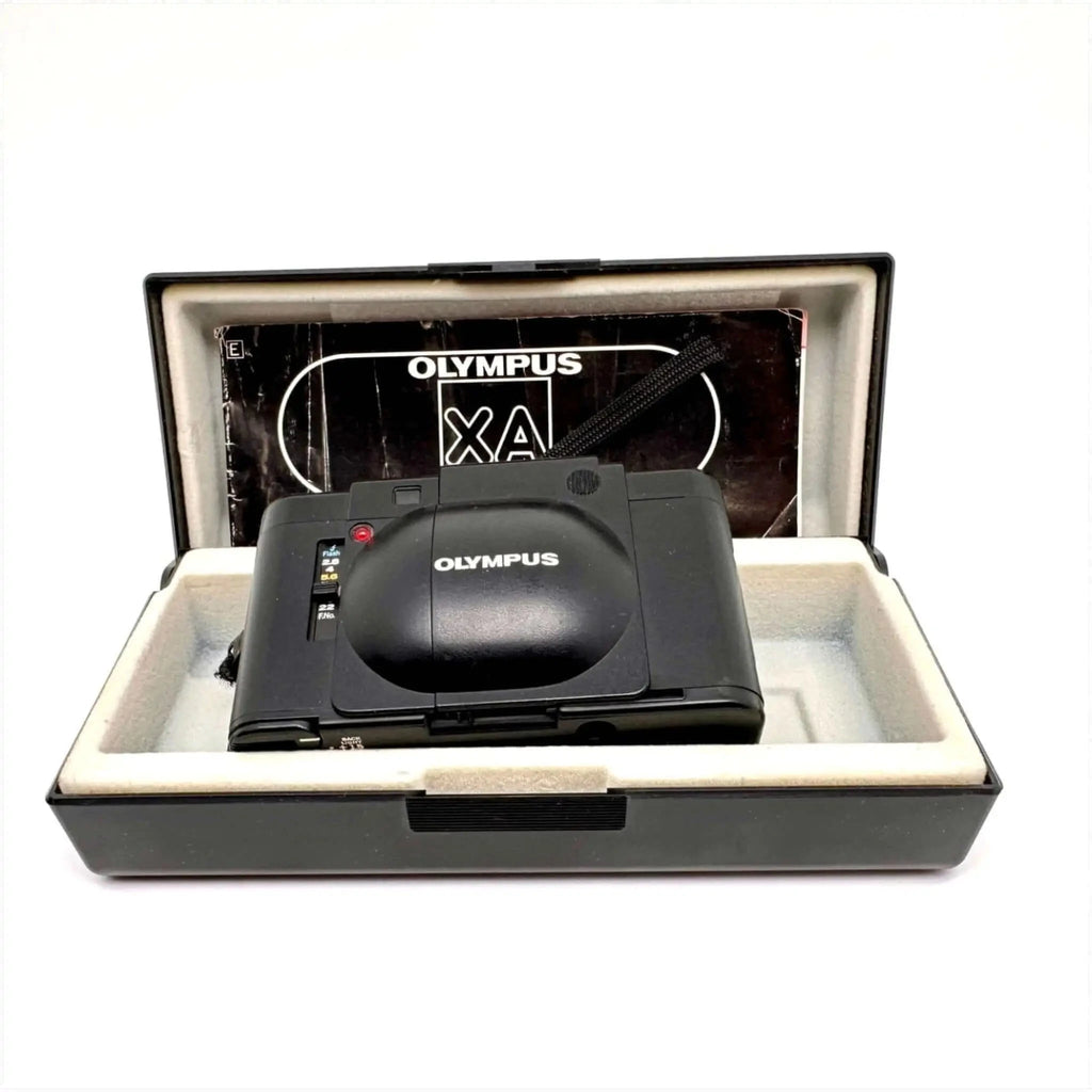 Black olympus xa compact camera with a glossy finish, nestled in its original case.