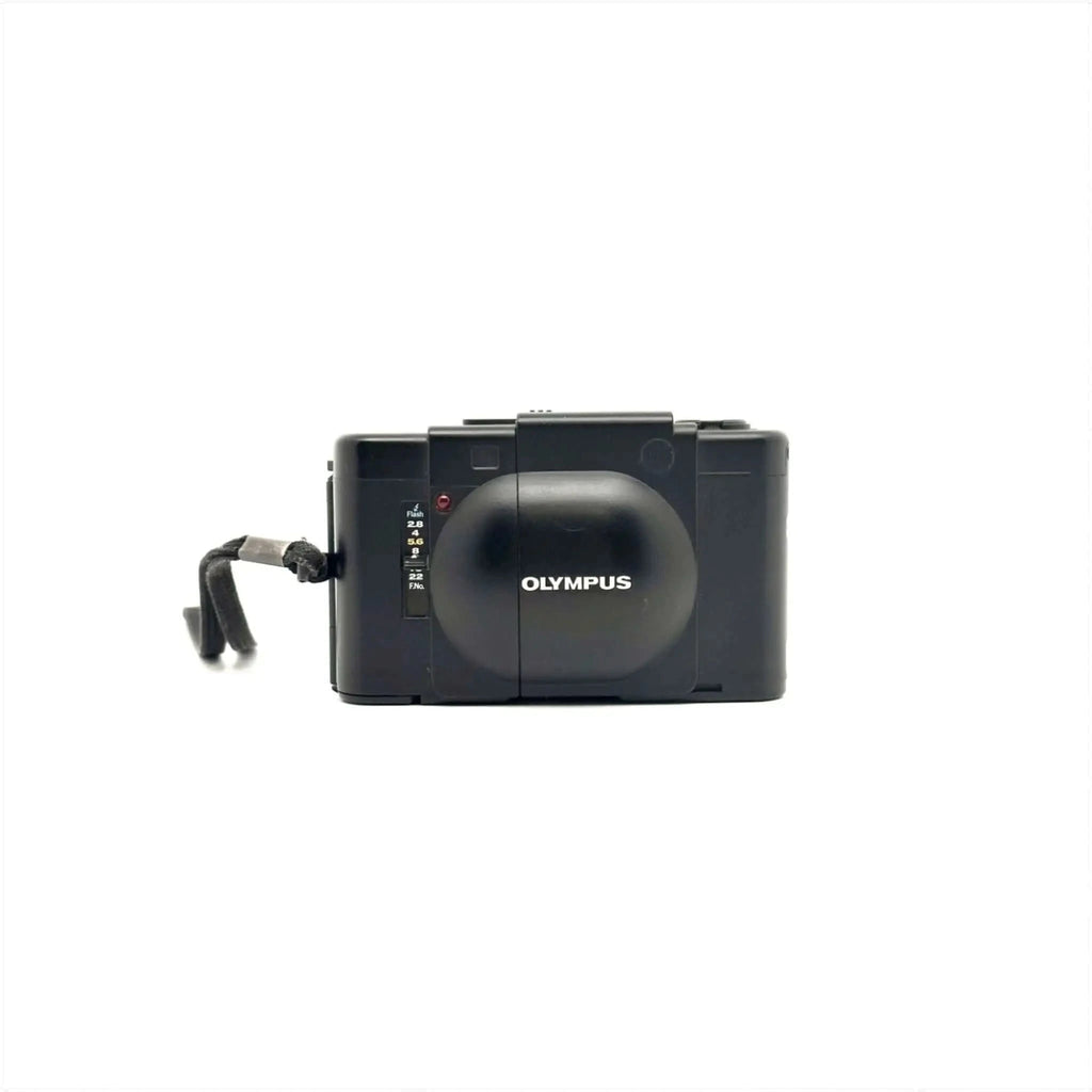 Black olympus digital camera with a rounded lens cover and a textured grip.