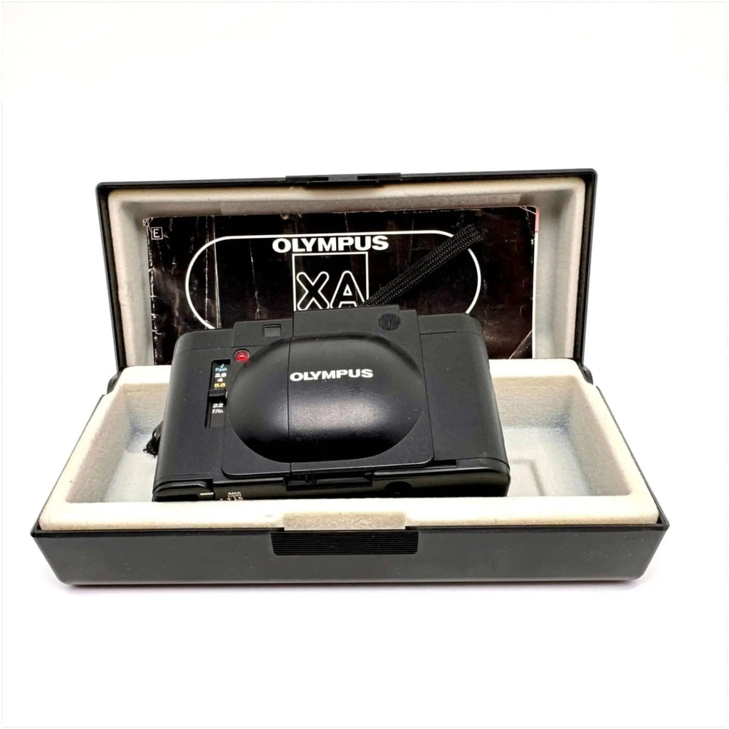 Black olympus xa compact camera with a glossy finish, nestled in its original case.