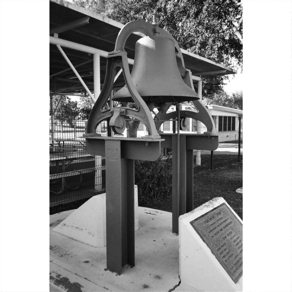 Black and white photo of a historic bell monument with an information plaque.