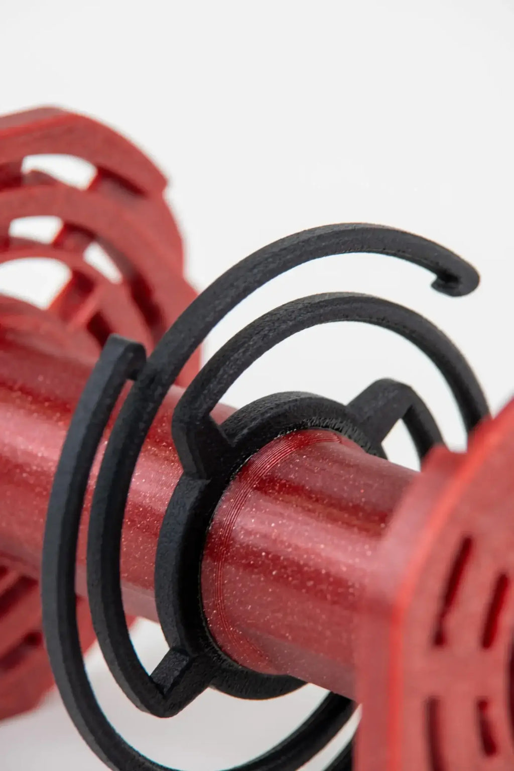 Red and black 3d-printed dumbbell weight holder with a spiral design.